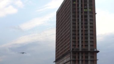 Düşük açılı döner kamera, üzerinde uçan bir uçak olan büyük şehir binaları.