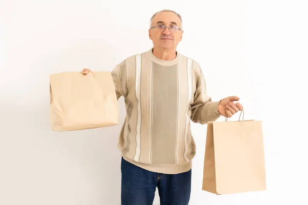Portret van gepensioneerde bejaarde gepensioneerde vrolijke grijsharige man koopt goederen geïsoleerd over een heldere achtergrond — Stockfoto
