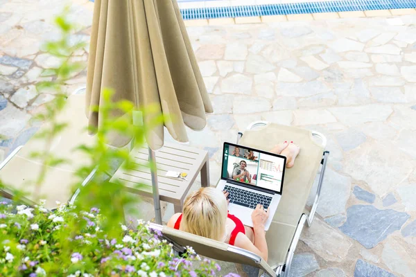 Front view of happ woman using laptop while relaxing on a sun lounger in the backyard at home. Summer fun at home by the swimming pool — Stock Photo, Image