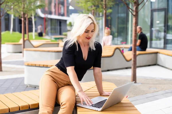 스마트 워치를 착용하고 랩탑 컴퓨터를 사용하는 젊은 여성. 옥외 카페에서 노트북으로 일하는 여자들. — 스톡 사진