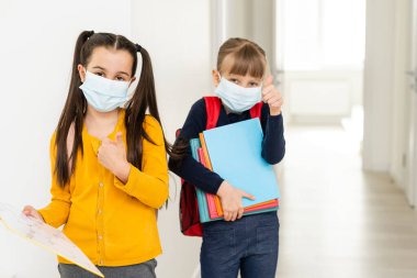 Küçük tatlı kızlar maske takıp birbirlerine sarılıyorlar. Liseli kızlar ellerinde defterler taşıyorlar ve okula girmeden önce birbirlerini selamlıyorlar..