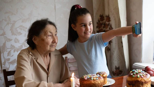 La abuela muy vieja y la nieta colorean los huevos, preparando el pastel de Pascua para la Pascua en casa. —  Fotos de Stock