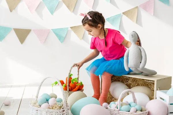 Готуємося до Великодня. Прекрасна маленька дівчинка тримає пасхальне яйце і посміхається з прикрасою на задньому плані — стокове фото