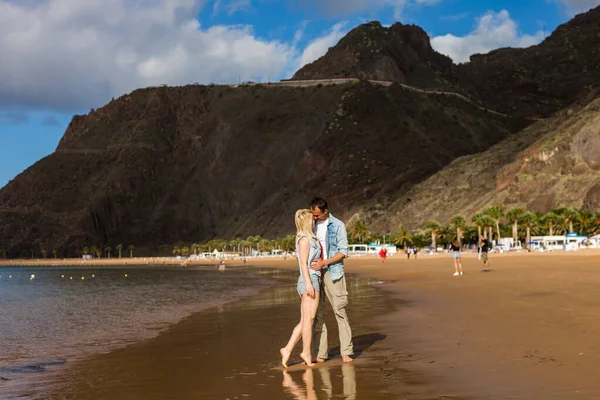 Pareja de vacaciones caminando juntos en la playa en el amor abrazándose unos a otros. Feliz pareja joven interracial — Foto de Stock