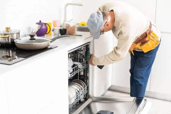 Bir evde bulaşık makinesini tamir eden teknisyen ya da tesisatçı. — Stok fotoğraf