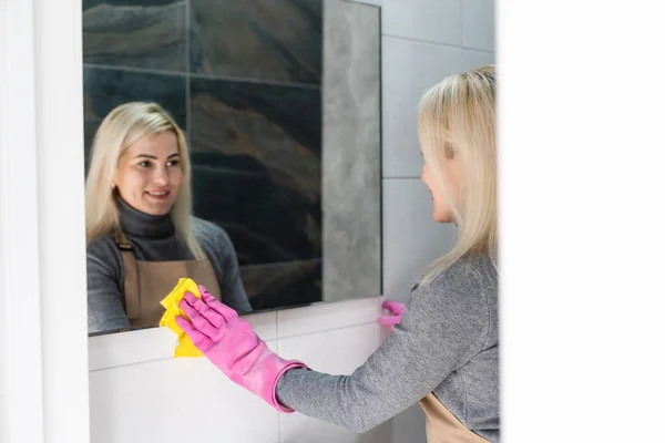 Blisko kobiety sprzątającej lustro w łazience — Zdjęcie stockowe