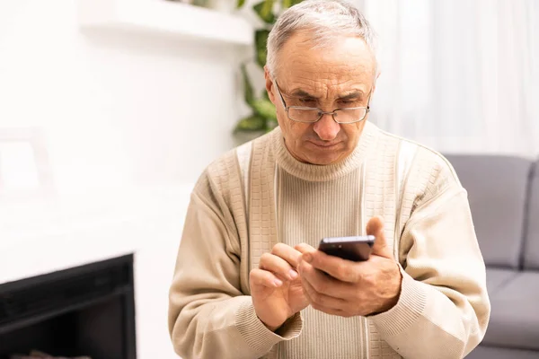 Технології, люди, спосіб життя та концепція спілкування щасливий старший чоловік набирає номер телефону та смс на смартфоні вдома . — стокове фото