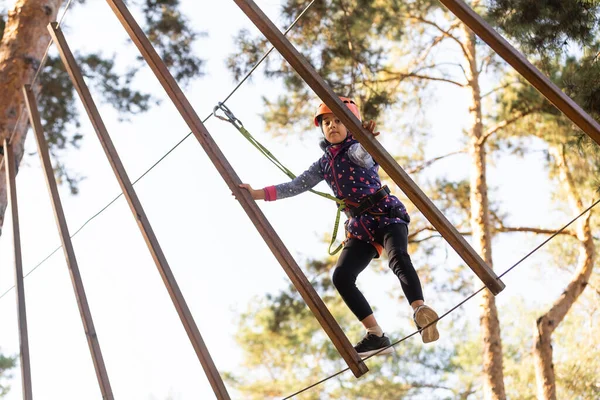 Dziewczyna wspinaczki w parku rozrywki to miejsce, które może zawierać szereg elementów, takich jak liny wspinaczkowe ćwiczenia, przeszkoda kursy i linii zip. — Zdjęcie stockowe