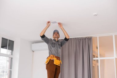 Apartmanın içine elektrik lambaları döşeyen elektrik işçisi. İnşaat dekorasyonu kavramı.