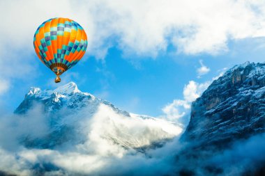 Karlı dağın üzerinde uçan renkli sıcak hava balonu