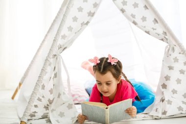 Evde rahat oturma odasında kitap okuma güzel küçük kız Portresi