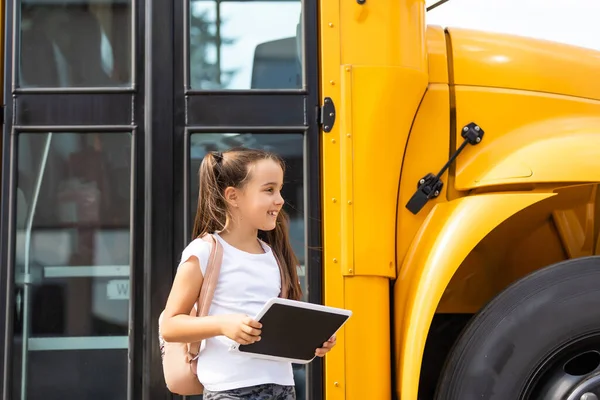 Egy lány hátizsákkal a sárga iskolabusz közelében. Diákszállítás — Stock Fotó