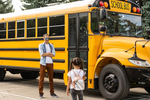 Водитель кузнечного автобуса смотрит на камеру возле школы — стоковое фото