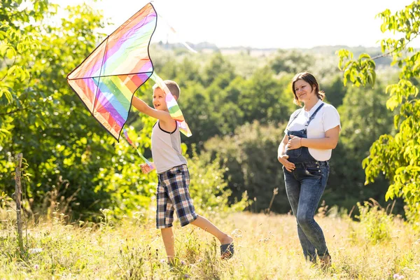 Embarazada con su hijo jugando una cometa — Foto de Stock
