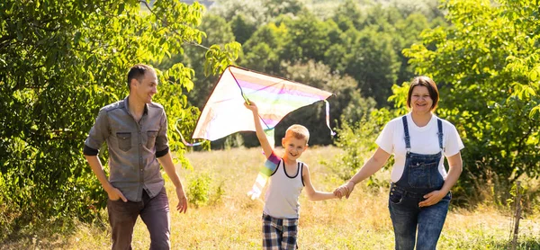A fiatal szülők a fiúval mennek a búzamezőre. A kisfiú boldog, ha kijátsszák.. — Stock Fotó