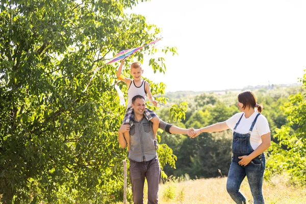 Los padres jóvenes van con el hijo al campo de trigo. El pequeño hijo es feliz cuando es interpretado. — Foto de Stock