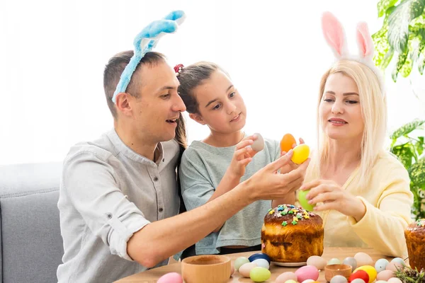 Rodina komunikuje online pomocí speciálního programu s přáteli na Velikonoční prázdniny. Webová konference prostřednictvím videohovoru na tabletu jeho kolegům. Zdobený stůl s květinami a barevnými vejci — Stock fotografie