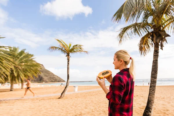 Frau posiert in Palmenblättern auf einer Insel mit tropischen Früchten in der Hand — Stockfoto