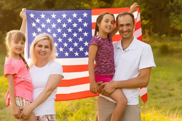 Happy family in field with USA, american flag on back. — Stock Photo, Image