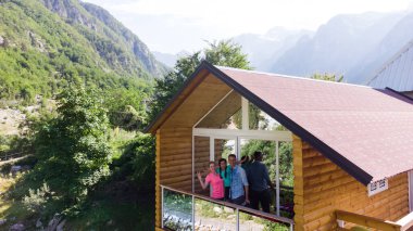 Aile dağ tepe tepe ve güneş üzerinde ahşap kulübe verandada