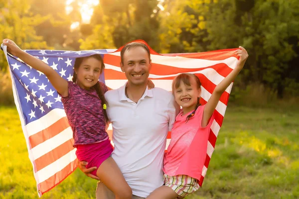 Happy family with the American flag in a wheat field at sunset. Independence Day, 4th of July. — Stock Photo, Image