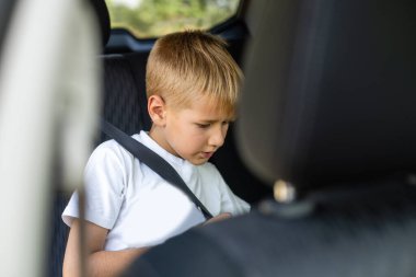 Arabadaki emniyet kemeri ile bükülmüş genç küçük çocuk