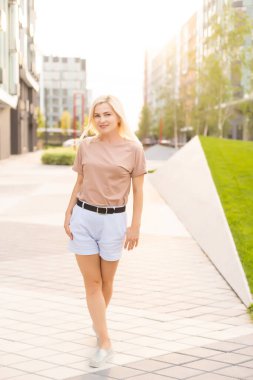 Genç, güzel, neşeli bir kadın sokakta yürüyor. Güzel kız sana bakıyor ve gülümsüyor.