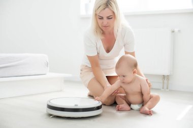 Küçük bebek evdeki robot elektrik süpürgesine bakıyor..