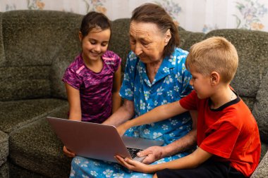 Çocuklu büyük büyükanne. - Aile. Okul çocuğu ve küçük kız çocuğu. Mutlu yaşlı kadınlar ve torunlar, içeride. dizüstü