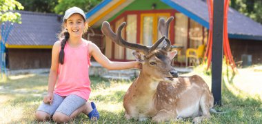 Küçük kız bir ren geyiğiyle duruyor.