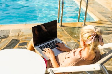 Yüzme havuzunda dizüstü bilgisayar kullanan bir kadın.