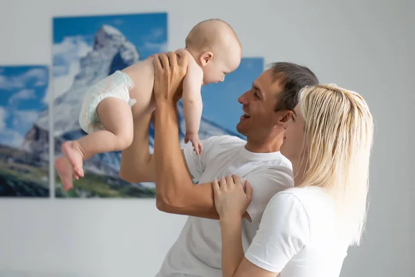 Egy boldog fiatal család babával a fehér hálószobában — Stock Fotó
