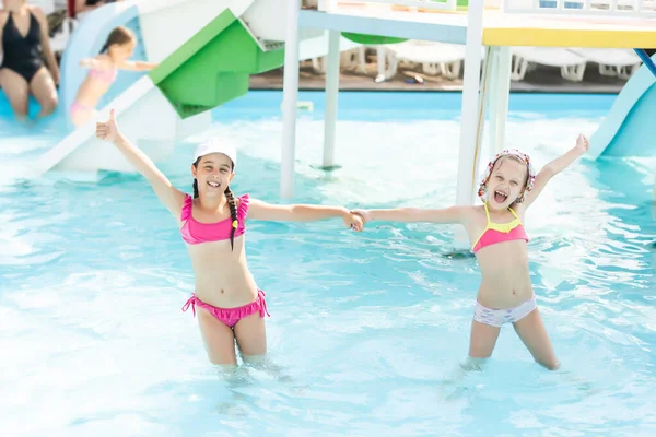 Две маленькие девочки весело прыгать в бассейн — стоковое фото
