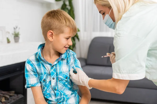 Coronavirus, griep of mazelenvaccin concept. Medic, doctor, verpleegkundige, gezondheidswerker vaccineert tienerjongen met vaccin in spuit. Ze draagt uniform en handschoenen.. — Stockfoto