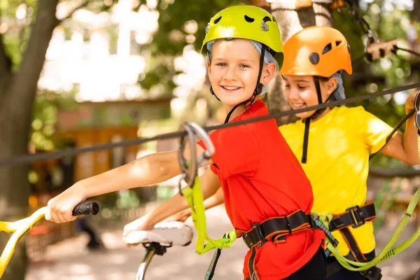 Aventura escalada parque de alambre alto - niño pequeño en curso en casco de montaña y equipo de seguridad — Foto de Stock