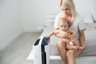 Anne ve bebek evde hava temizleyicinin yanında..