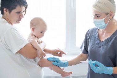 Doktor beyaz arka planda bebek aşısı yapıyor..