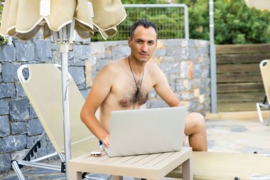 Dizüstü bilgisayarı olan bir adam bilardo salonunun yanında dinleniyor.