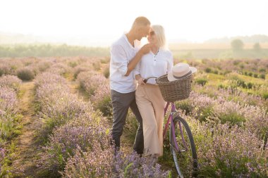 Romantik genç çift, yaz tatili boyunca erkek ve kadın lavanta tarlasında eğleniyorlar.