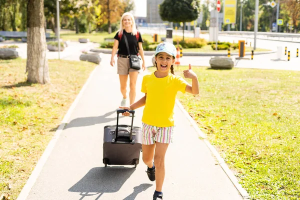 Madre e hija pequeña van con maletas al aeropuerto. turismo y viajes. —  Fotos de Stock