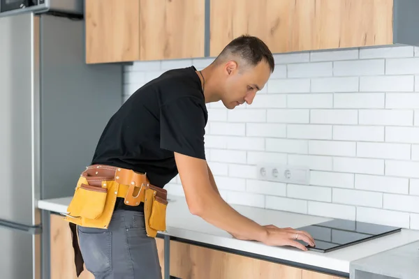 Junger Reparateur installiert Induktionsherd in Küche — Stockfoto