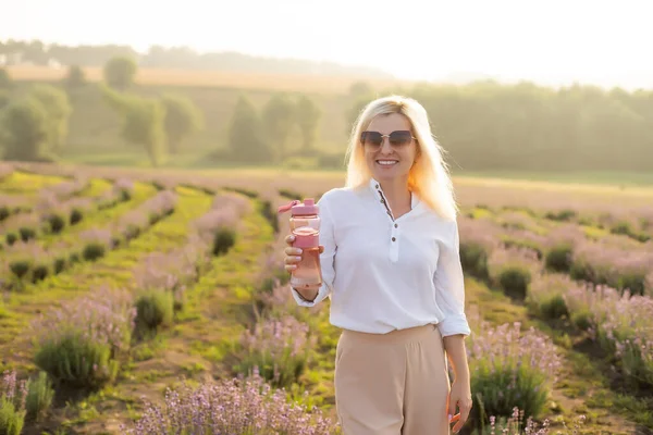 Woman with bottle of water in lavender field — Stock Fotó