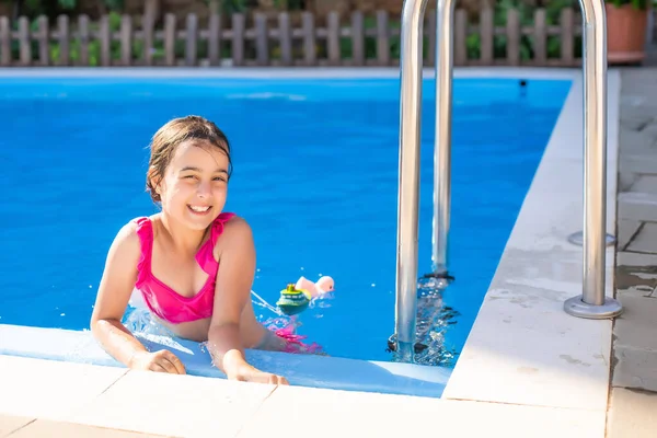 सुंदर छोटी लड़की आउटडोर पूल में तैर रही है और एक मज़ा है — स्टॉक फ़ोटो, इमेज