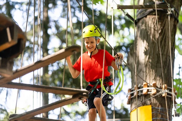 Aventura escalada parque de alambre alto - niño pequeño en curso en casco de montaña y equipo de seguridad —  Fotos de Stock