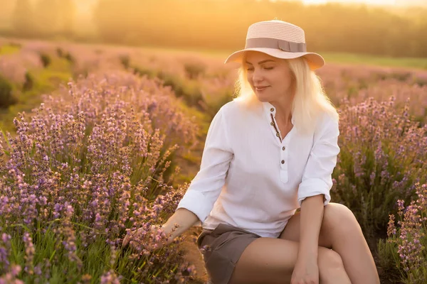 Młoda blondynka kobieta podróżnik noszenie słomy kapelusz w lawendy pole otoczone lawendy kwiaty. — Zdjęcie stockowe