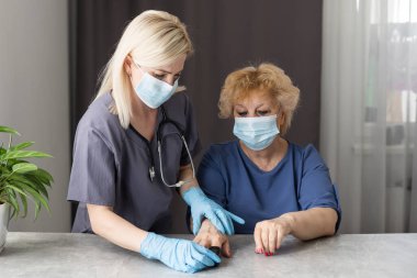 Doktor, yaşlı kadın hastayla hastalık belirtileri hakkında konuşmak, doktor yaşlı hastayla parmak ucu nabız oksimetresi, yaşlı sağlık kontrolü ve sağlık taraması, tıbbi teknoloji
