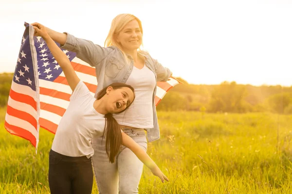 Patriotic holiday. Happy family, mother and her daughter child girl with American flag outdoors. USA celebrate 4th of July — Stock Photo, Image