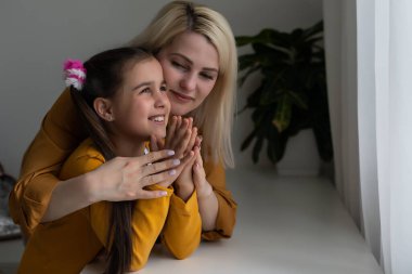 Anne ve kız İncil okuyor ve dua ediyor.