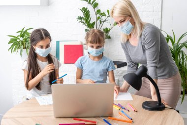 Evde çocuklu bir kadın internet öğretmenine yardım ediyor. Coronavirüs.