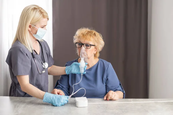 年轻女医生为老年女性患者戴氧气面罩. — 图库照片
